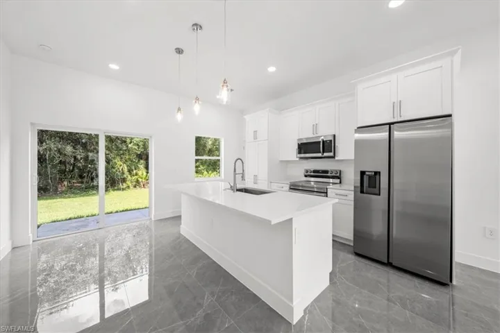 Kitchen featuring appliances with stainless steel finishes, a kitchen island with sink, white cabinetry, light countertops, and recessed lighting