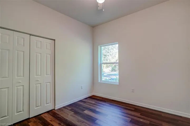 Unfurnished bedroom with baseboards, a closet, ceiling fan, and dark wood-style flooring