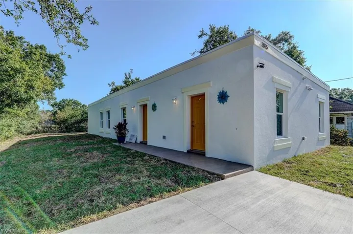 View of front of property with a patio, a front yard, and stucco siding
