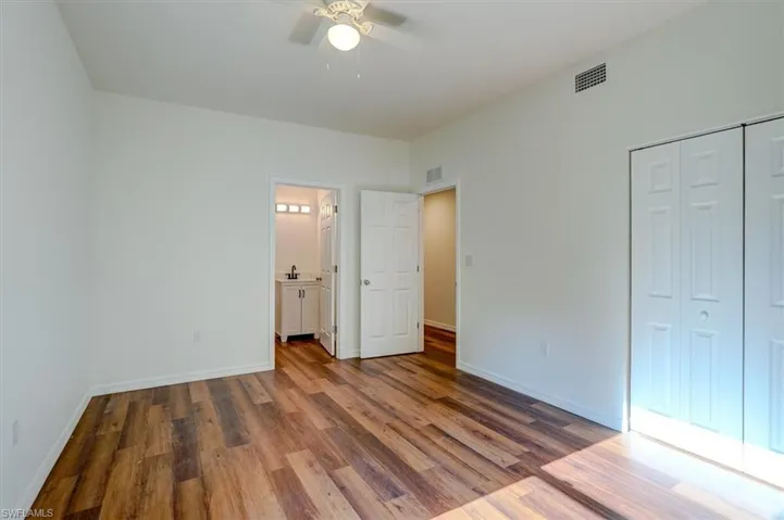 Unfurnished bedroom with wood finished floors, visible vents, a ceiling fan, a closet, and baseboards