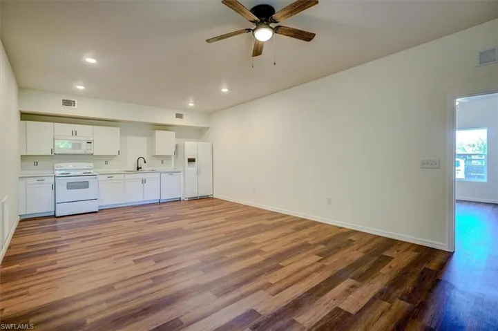 Kitchen with visible vents, wood finished floors, white appliances, and a sink