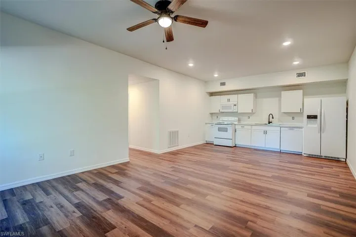 Unfurnished living room featuring recessed lighting, wood finished floors, visible vents, and a sink