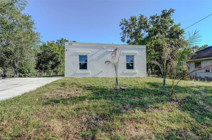 View of front of house featuring a front yard, stucco siding, and fence