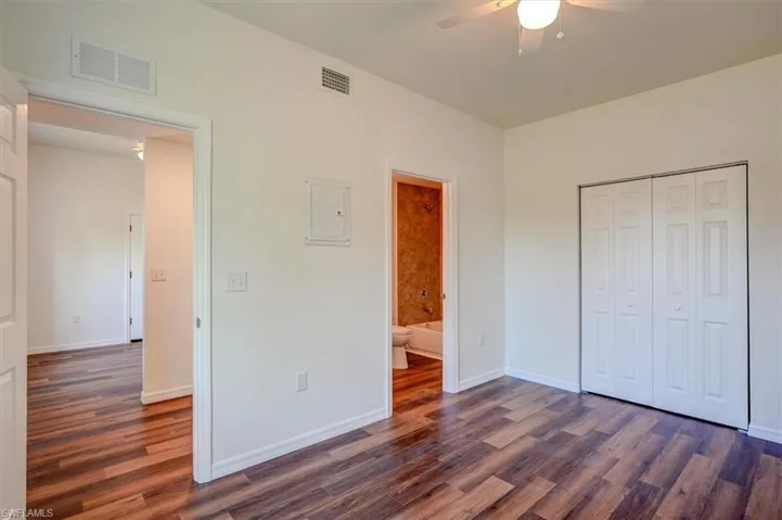 Unfurnished bedroom with baseboards, visible vents, and dark wood-type flooring