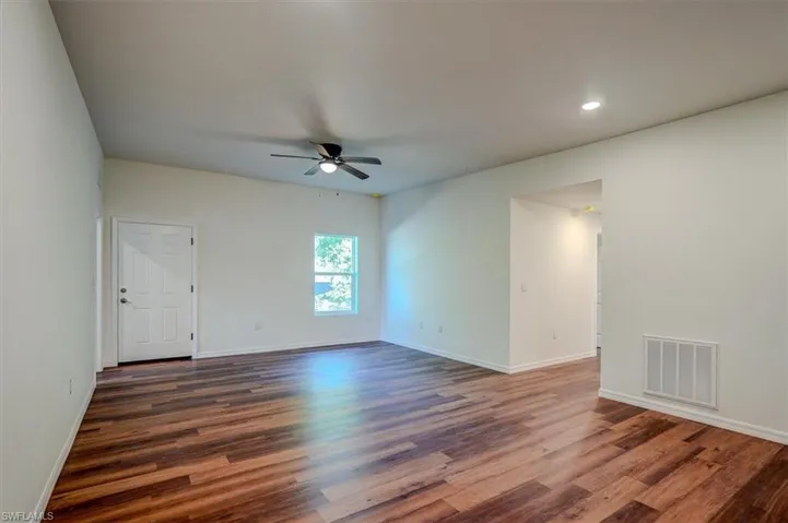Empty room with dark wood finished floors, baseboards, visible vents, recessed lighting, and a ceiling fan
