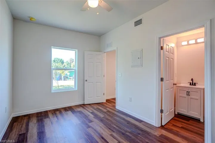 Unfurnished bedroom featuring baseboards, visible vents, dark wood-style floors, and a sink
