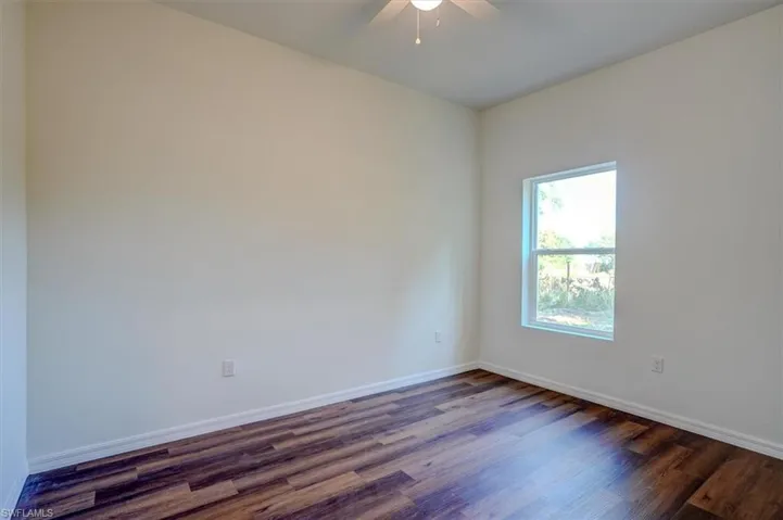 Spare room featuring a ceiling fan, baseboards, and dark wood-style flooring