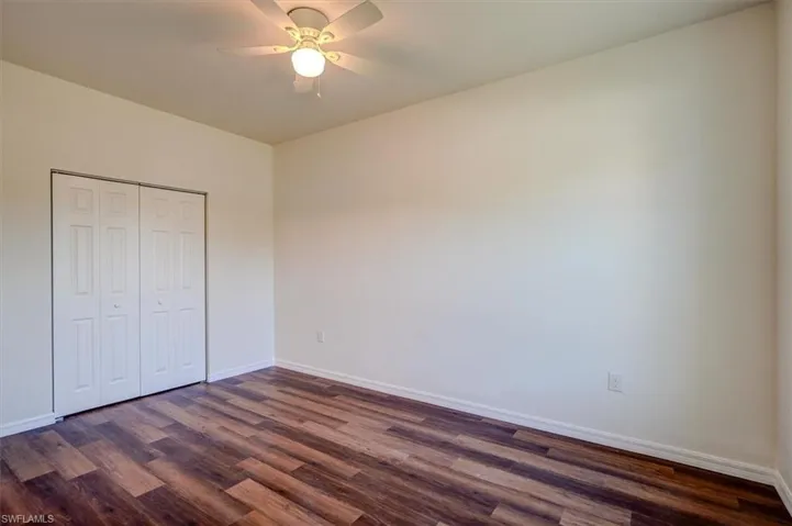 Unfurnished bedroom featuring dark wood finished floors, a closet, and baseboards