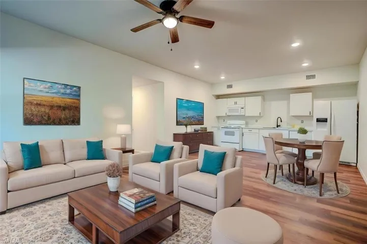 Living room featuring light wood-type flooring, a ceiling fan, visible vents, and recessed lighting