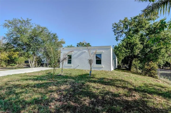 View of side of home with fence, a lawn, and stucco siding