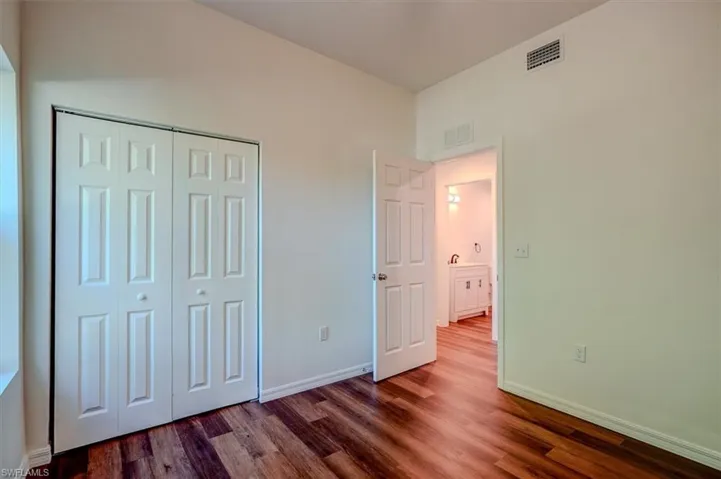 Unfurnished bedroom featuring wood finished floors, visible vents, and baseboards