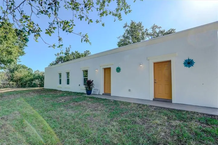 Rear view of house featuring a lawn and stucco siding