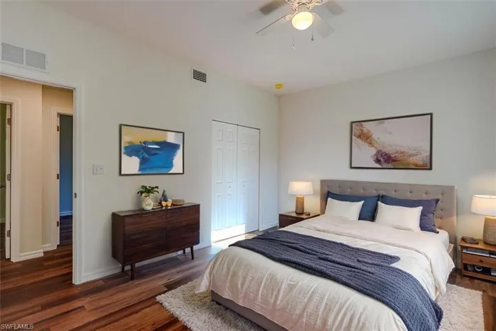 Bedroom with a closet, wood finished floors, visible vents, and baseboards