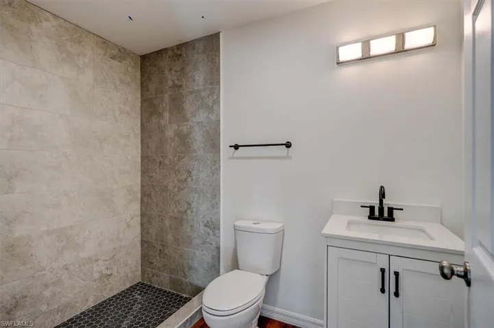Bathroom with a tile shower, vanity, and toilet