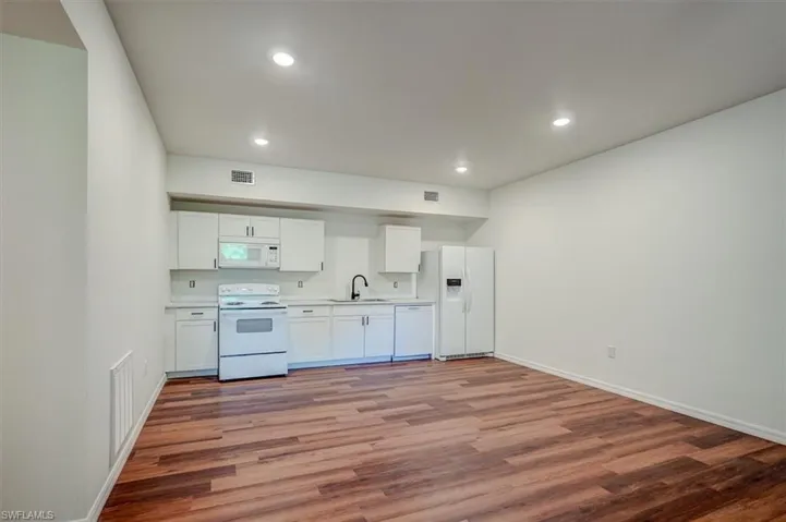 Kitchen with light wood-style floors, visible vents, a sink, and white appliances
