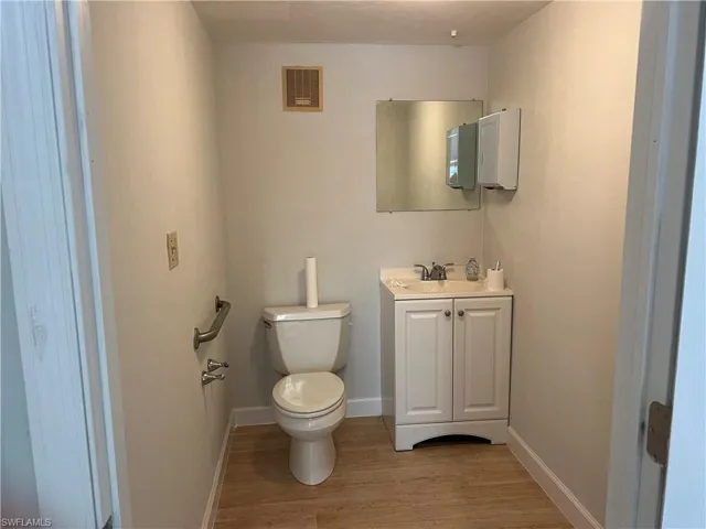 Bathroom with hardwood / wood-style flooring, vanity, and toilet