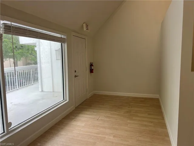 Doorway to outside featuring lofted ceiling, plenty of natural light, and light wood-type flooring