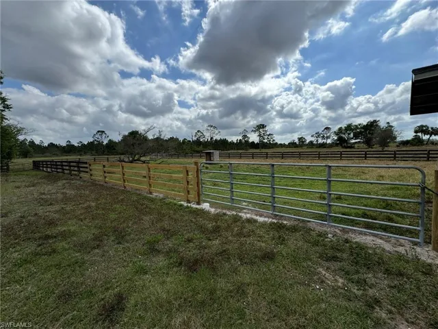 View of gate featuring a rural view, a lawn, and fence