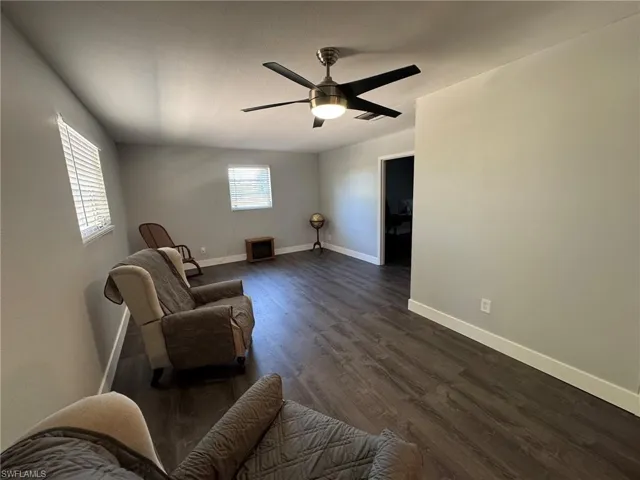 Sitting room featuring ceiling fan, visible vents, baseboards, and dark wood-style flooring