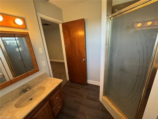 Full bathroom with baseboards, visible vents, wood finished floors, and vanity