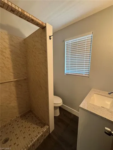Full bath with a textured ceiling, toilet, wood finished floors, vanity, and baseboards