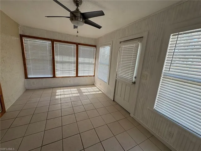 Unfurnished sunroom featuring a ceiling fan