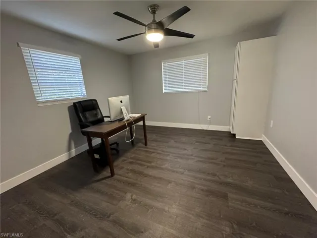 Office space with ceiling fan, dark wood-style flooring, and baseboards