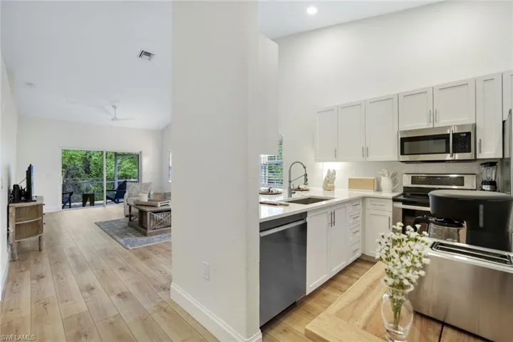 Completely renovated kitchen features lofted ceiling, custom wood cabinetry, stainless steel appliances, stone countertops, large pantry for additional storage, and light wood-style floors