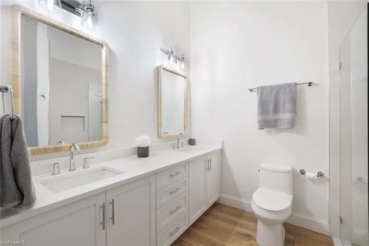The primary bathroom has been totally renovated and includes custom cabinetry, contemporary wood-style flooring, cathedral ceiling, dual vanity and sinks, and new toilet