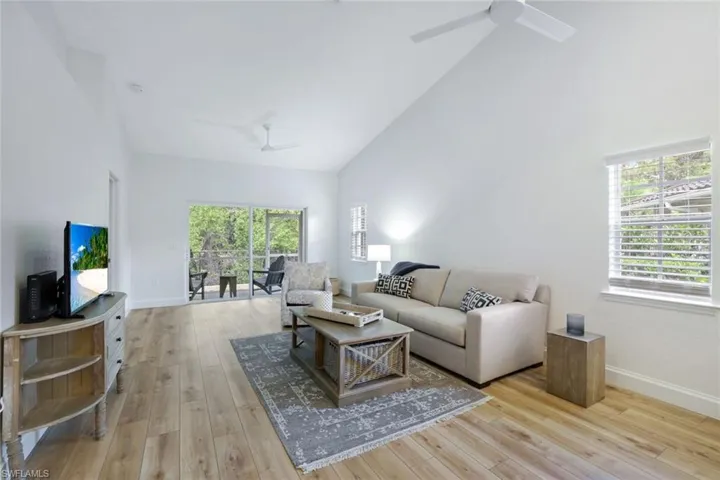 The living room features cathedral ceiling, a gorgeous amount of natural light, ceiling fans, and contemporary light wood-style flooring throughout