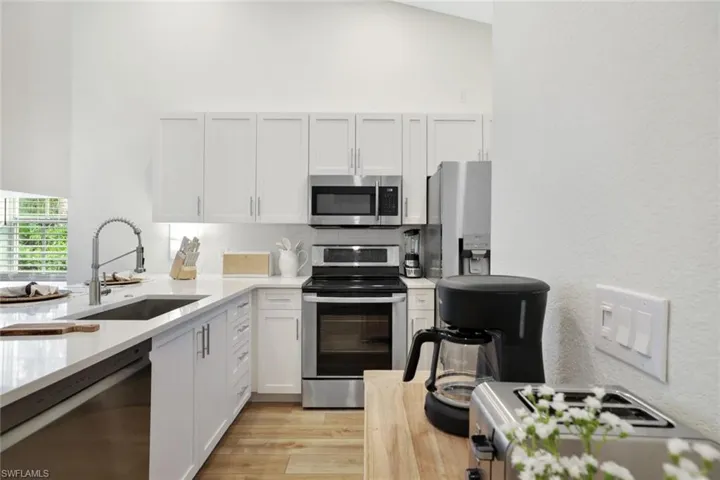 Completely renovated kitchen features lofted ceiling, custom wood cabinetry, stainless steel appliances, stone countertops, large pantry for additional storage, and light wood-style floors