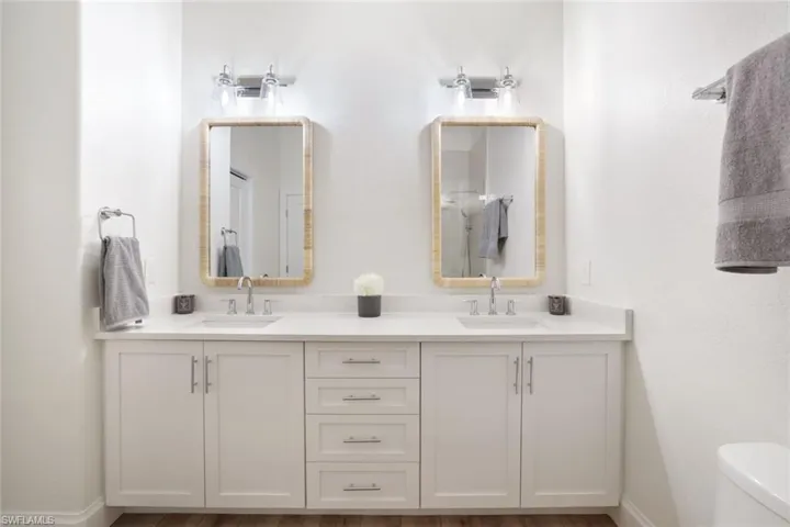 The primary bathroom has been totally renovated and includes custom cabinetry, contemporary wood-style flooring, cathedral ceiling, dual vanity and sinks, and toilet