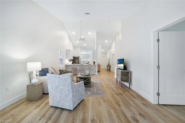 The living room features cathedral ceiling, a gorgeous amount of natural light, ceiling fans, and contemporary light wood-style flooring throughout