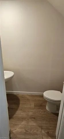 Wood-finish flooring with a wall-mounted sink and white toilet