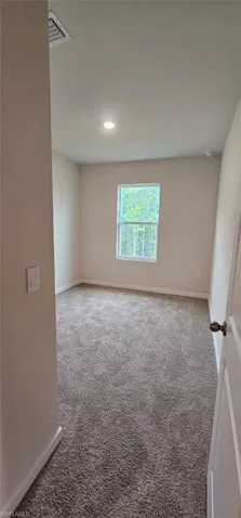 Neutral wall paint, recessed lighting, gray carpet flooring, and a single window