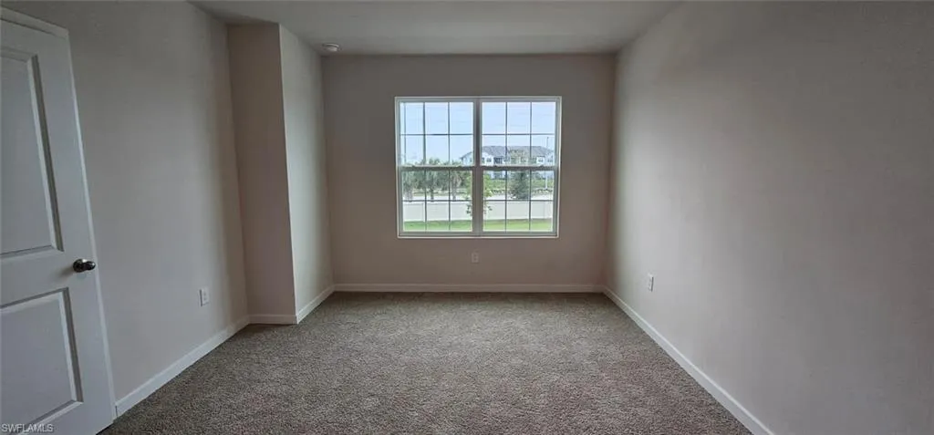 Window with grid panes, textured carpeting, and neutral wall tones