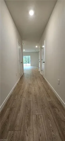 Wood-finish flooring, recessed lighting, and crisp white walls define this hallway