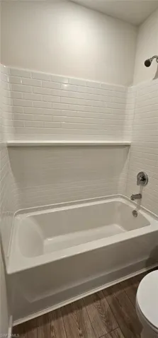 White subway tile shower surround with integrated shelf, chrome shower head, and tub filler
