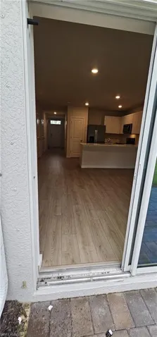 Open concept living area featuring wood-finish flooring, recessed lighting, and a kitchen with white cabinetry and stainless steel appliances