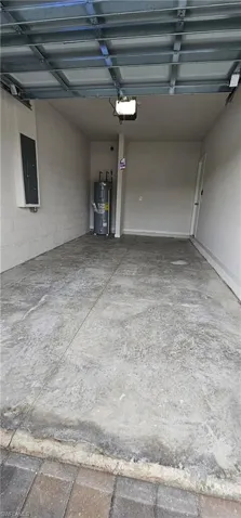 Attached garage with concrete flooring, automatic garage door opener, and white painted walls