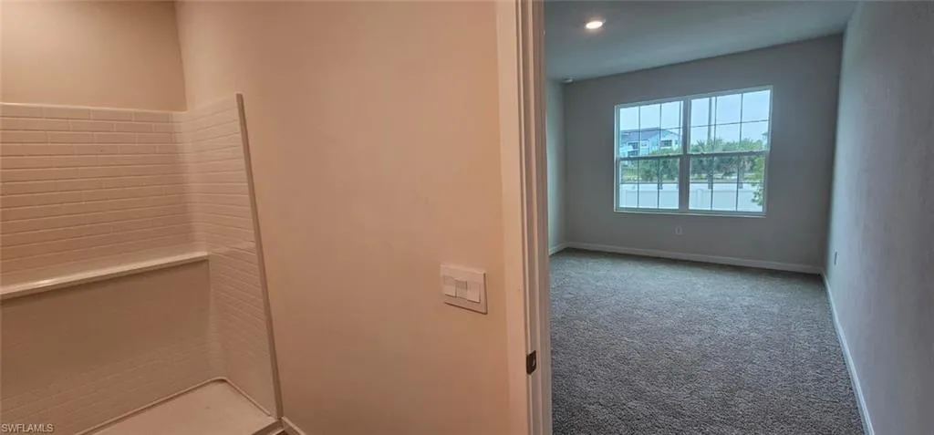 Bright secondary bedroom featuring neutral wall finishes, carpet flooring, and abundant natural light from a large multi-pane window