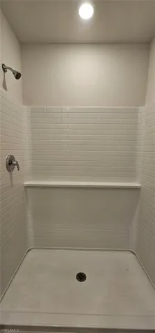 Shower stall featuring subway tile, integrated shelving, and a dark-finish shower head
