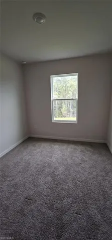 Neutral tone wall finishes, gray carpeting, recessed ceiling lighting, and a window with white trim