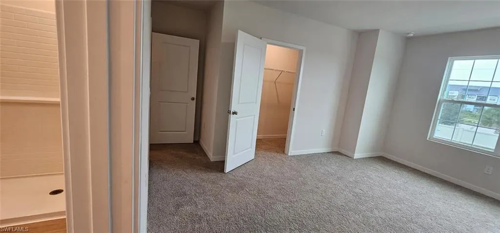 Carpeted room with white walls, a window, and a closet with wire shelving