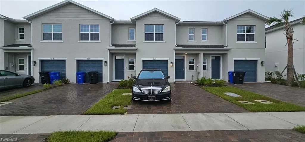 Stucco exterior with gabled accents, single-car garage with dark blue door, paved driveway, and established landscaping