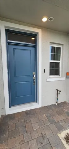 Entryway featuring a paneled door with transom window, recessed lighting, grid-patterned window, and paver flooring