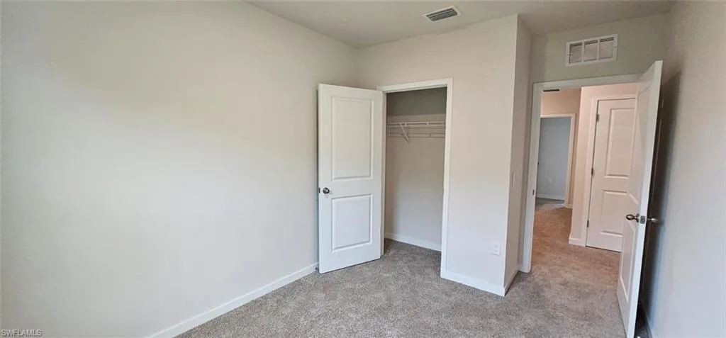 Plush carpet flooring, neutral wall tones, white trim, and a built-in closet with wire shelving