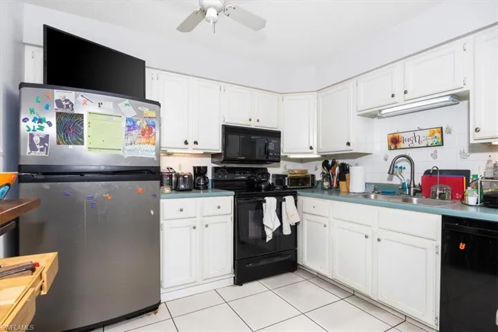 Kitchen with black appliances, white cabinets, ceiling fan, light tile patterned flooring, and backsplash