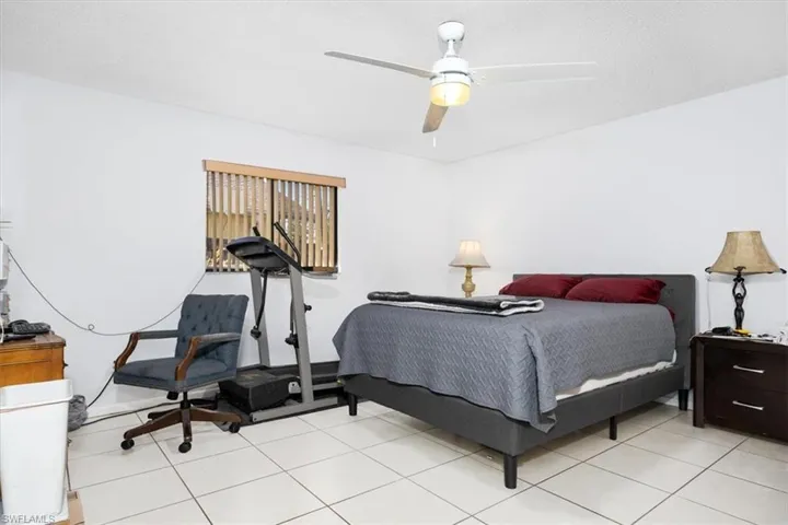 Bedroom with ceiling fan, a textured ceiling, and light tile patterned flooring