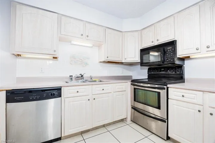 Kitchen with stainless steel appliances, light countertops, and light tile patterned floors